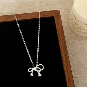 Detailed view of silver bow necklace with bead pendants on a professional display board