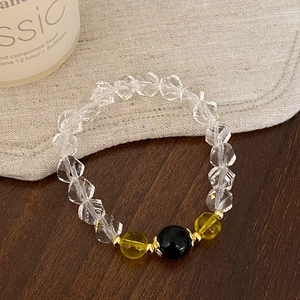 Elegant beaded bracelet with clear crystals and black onyx charm on a rustic table