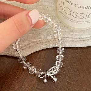 Elegant beaded crystal bracelet with silver bow pendant on a warm textured background