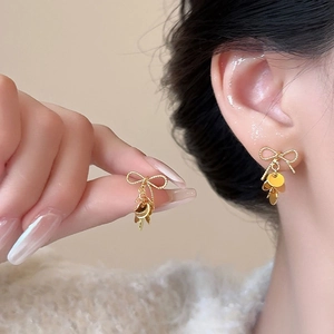 Elegant gold bow earrings with sequin tassels and twisted rope texture on a model