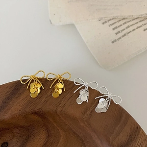 Detailed close-up of bow knot earrings with hanging discs in gold and silver finish