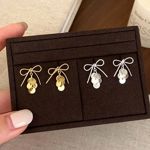 Detail of elegant gold and silver bow stud earrings with dangling metal sequins