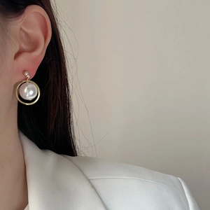 Elegant gold ring earrings with floating white pearl pendant on model in white blazer