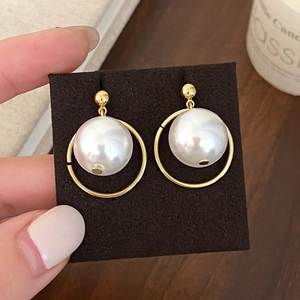 Detail of elegant pearl heart pendant earrings on a gold hoop with stud attachment