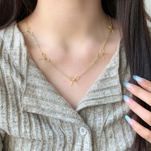 Elegant gold bow pendant necklace on model with minimalist style for women