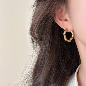 Close-up of matte gold twisted hoop earring with elegant braided texture and metallic finish