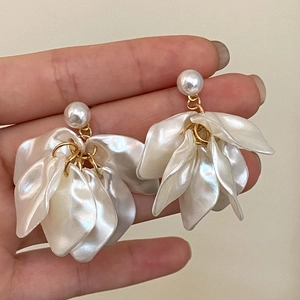 Handheld view of elegant white petal tassel earrings with pearls and gold metal links
