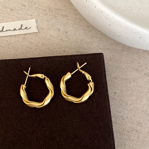 Detailed view of matte gold twisted hoop earrings on a vintage jewelry display