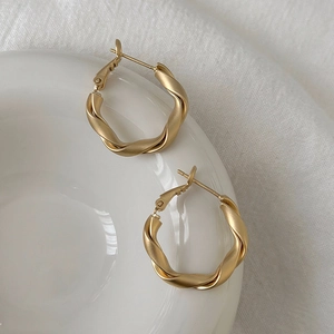 Macro shot of matte gold twisted hoop earrings showing refined satin texture details
