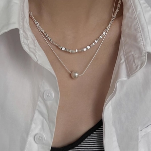 Detail of a double-layer silver necklace with irregular silver beads and a white pearl
