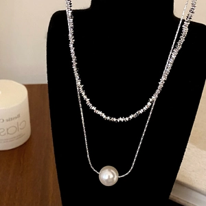 Close-up of double-layered silver-tone necklace with pearl pendant on display stand
