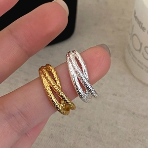 Cross-layered rings with hammered texture in gold and silver finish on finger