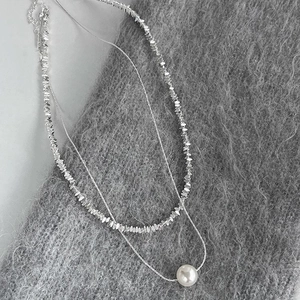 Detail of double-layer necklace with silver metallic flakes and a glossy white pearl pendant