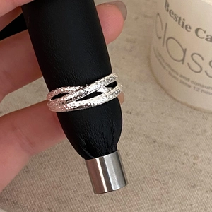 Detail shot of silver-toned ring with intricate hammered texture and crossover design