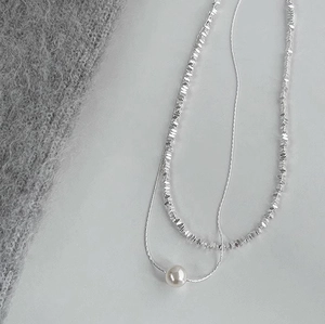 Detail of silver double-layer necklace featuring iridescent pearl and metallic beads