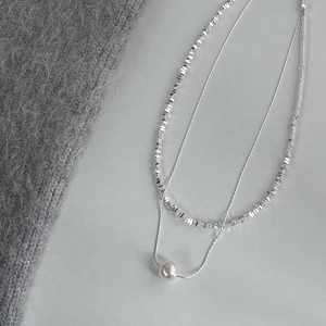 Detail of silver double-layered necklace featuring a white pearl pendant and silver beads