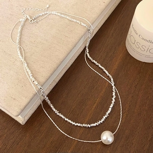 Close-up of double-layer silver necklace with metallic beads and large white pearl