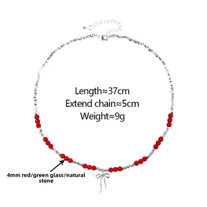 Close-up of beaded necklace with red gemstones, silver bow pendant and adjustable chain