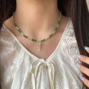 Elegant beaded collar necklace with green natural stones and silver bow pendant on model