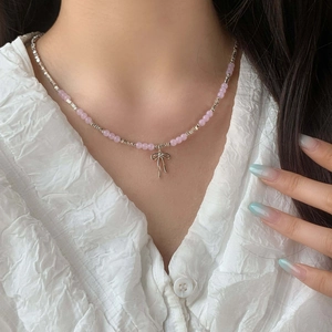 Pink gemstone bead choker necklace with a silver bow pendant worn by a model