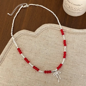 Detail of red bead necklace with silver bow pendant featuring adjustable lobster clasp