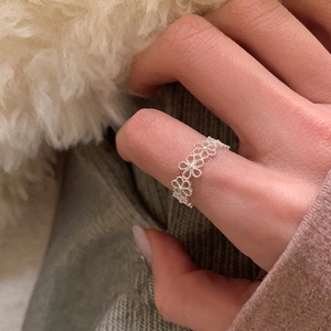 Nahaufnahme eines silbernen Rings mit durchbrochenem Blumenmuster auf Strickhintergrund