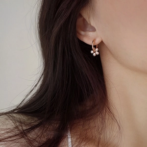 Close-up of rose gold flower earrings with micro-set diamonds on a female model