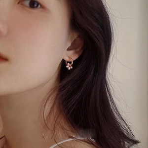 Close-up of rose gold hoop earrings with sparkling crystal flower charms on model