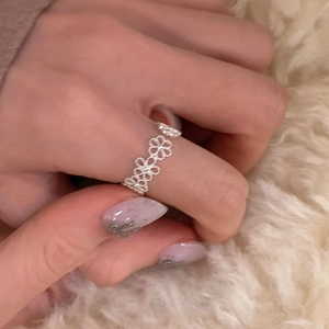 Nahaufnahme eines silbernen hohlen Blumen-Spitzenrings am Finger mit lila Glitzer-Nägeln