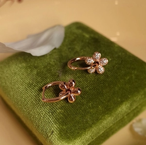 Detail of rose gold flower earrings with pavé stones on a green velvet jewelry box