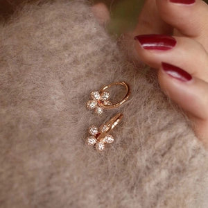 Detailed view of flower-shaped rose gold earrings with pave-set shimmering crystals
