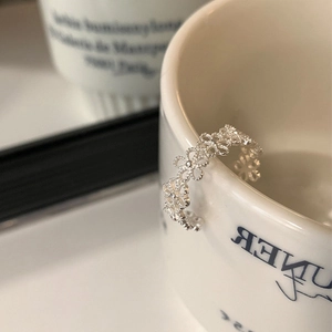 Detailansicht eines silbernen Blumenrings mit Durchbruchmuster an einer Tasse