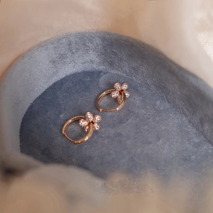 Detail shot of rose gold flower earrings with pavé crystals in a blue velvet box