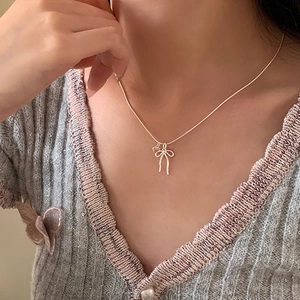 Elegant bow and heart zircon necklace with sleek snake chain shown on a model's neck