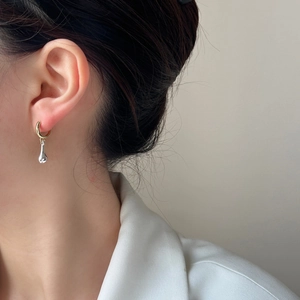 Créoles dorées minimalistes avec pendentifs goutte d'argent portées par un mannequin