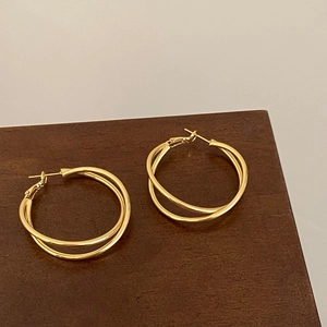Boucles d'oreilles créoles doubles dorées torsadées sur socle en bois