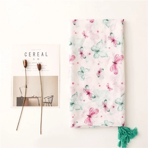 Sciarpa in cotone e lino con stampa a farfalla e nappe decorative su uno sfondo bianco