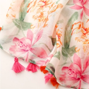 Detail of red floral printed scarf with vibrant pink and orange tassels on cotton linen