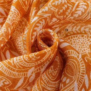 Macro shot of orange paisley fabric with subtle sequins and linen-like texture