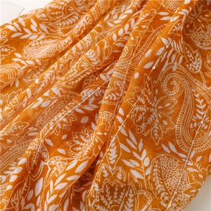 Macro shot of orange paisley voile scarf with shimmering sequins and linen texture
