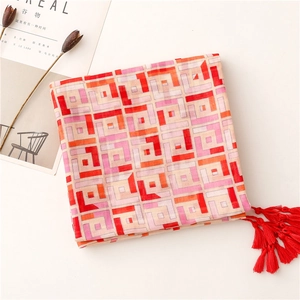 Detailed view of pink and orange geometric scarf with vibrant red fringe tassels