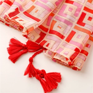 Detailed view of bohemian geometric pattern scarf with vibrant red fringe tassels