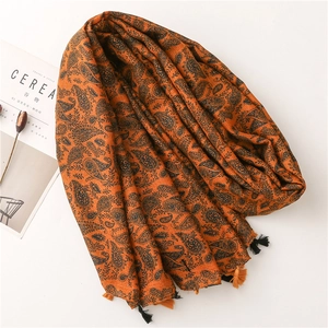 Dettaglio di sciarpa in cotone e lino arancione caramello con motivo paisley e frange morbide
