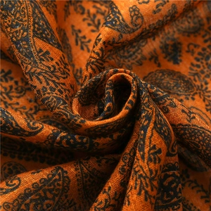 Dettaglio di scialle in cotone arancione con motivi paisley neri e frange artigianali