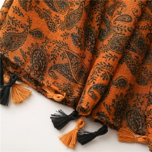 Dettaglio macro della sciarpa in cotone e lino con motivo paisley e morbide nappe