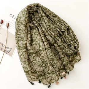 Dettaglio di sciarpa in cotone e lino verde scuro con motivo paisley e nappe