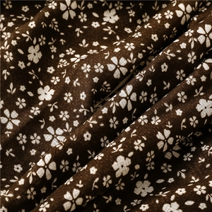 Dettaglio macro del tessuto in lino di cotone marrone scuro con motivo floreale e frange