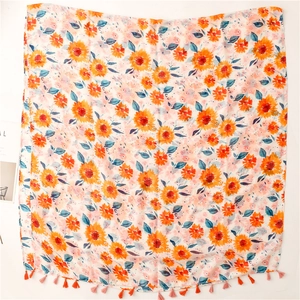 Detail of sunflower print shawl with vibrant fringe tassels on soft fabric