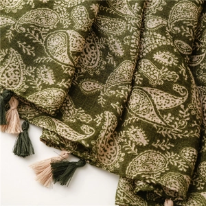 Dettaglio di scialle in cotone e lino verde scuro con motivo paisley e nappe bicolore