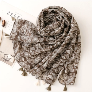 Dettaglio di sciarpa paisley marrone caffè con nappine decorative su sfondo di una rivista